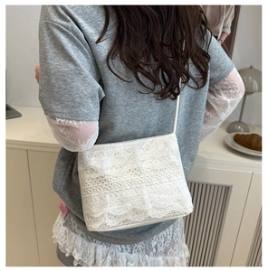 Close-up of white lace shoulder bag featuring intricate floral hollow textures and slim strap