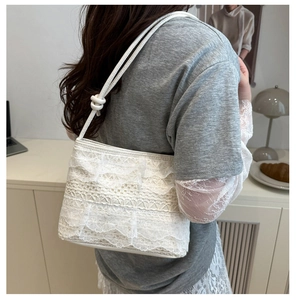 Detailed close-up of white lace shoulder bag with tiered ruffles and cord strap