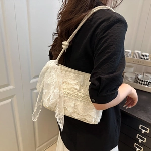 White lace shoulder bag with large bow detail shown on model in minimal interior