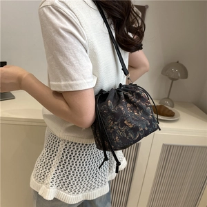Retro floral drawstring bucket bag with artistic print and slim black crossbody strap