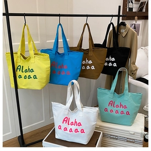 Detailed display of assorted canvas tote bags in six colors with bold art print lettering