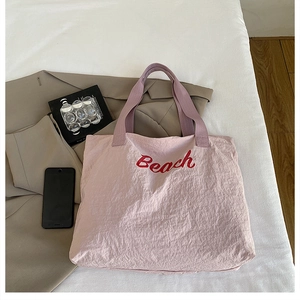 Gros plan du sac fourre-tout rose avec texte Beach rouge et texture froissée