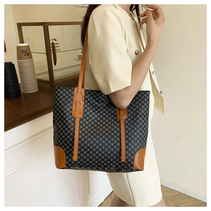 Macro detail of large tote bag showing black geometric texture and brown leather straps