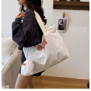 Détail du sac cabas en toile crème avec lettrage Beach rouge et sa pochette assortie