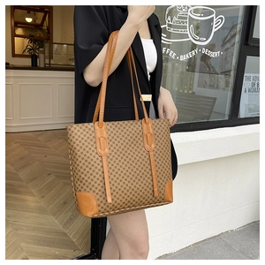 Brown printed tote bag with leather corner patches held by a model in a café setting