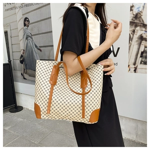 Close-up of large tote bag with geometric monogram pattern and brown leather trim
