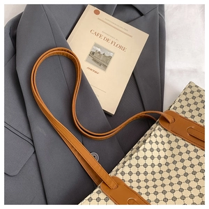 Close-up of geometric pattern tote bag with brown leather straps on grey blazer