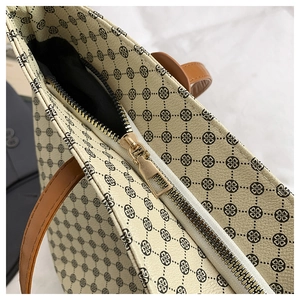 Detail of lychee pattern leather, black geometric prints and gold zipper on beige tote