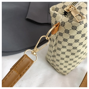Close-up of golden metal zipper and brown leather strap on a beige patterned tote bag