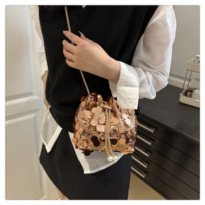 Close-up of golden sequin bucket bag with metal chain strap and pearl drawstring detail