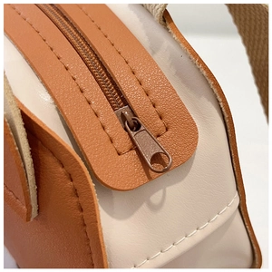Détails des coutures en cuir et du zip métallique de ce sac à bandoulière pour enfants