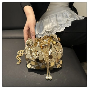 Close-up of a gold sequin bucket bag featuring a pearl drawstring and metal chain strap