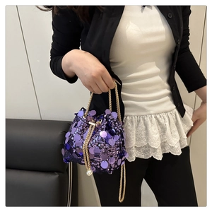 Detail of dark purple sequin bucket bag with pearl drawstring and gold chain strap