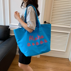 Large blue canvas tote bag with red Aloha print shown on a female model for daily commute
