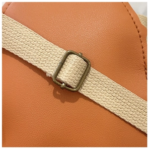 Détail du sac en similicuir caramel avec bandoulière crème et boucle en métal réglable
