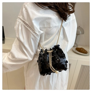 Detail of sequined bucket bag featuring drawstring closure with large pearl ornaments