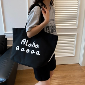 Large black canvas tote bag with white lettering and wide strap for daily shoulder use
