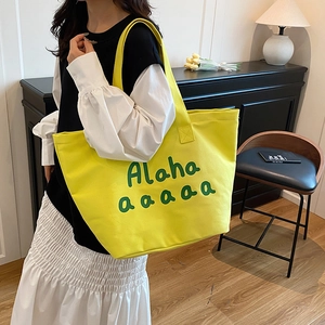 Large bright yellow canvas tote bag with green letters for daily commute or shopping