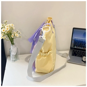 Dettaglio della borsa tote in nylon giallo con manici viola e tasca laterale per bottiglie