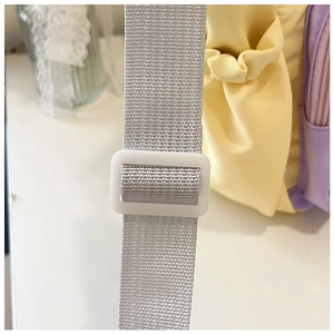Detail of grey adjustable nylon strap with white plastic buckle on a tote bag