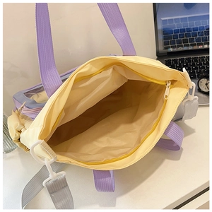 Detail of a yellow tote bag with purple handles showing a spacious interior for a laptop