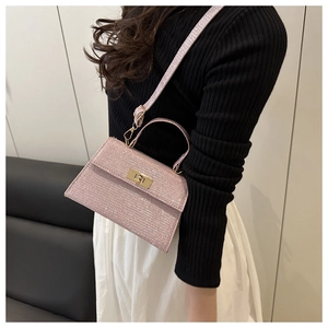Detailed close-up of sparkling pink glitter fabric and gold twist lock on stylish handbag