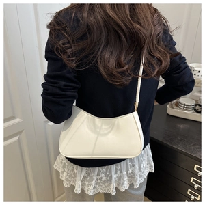 Sac à bandoulière blanc chic en forme de croissant porté par un mannequin en cuir