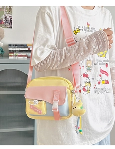 Détail du sac bandoulière en toile pastel avec breloque canard et sangle rose