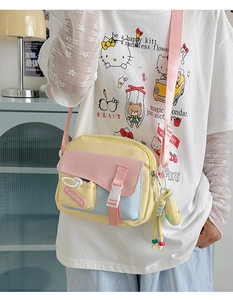 Vue macro du sac bandoulière jaune citron avec poche à boucle rose et logo détaillé