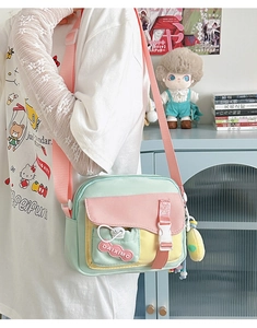 Détail du sac bandoulière en toile couleur bonbon avec panneaux pastel et charm en peluche