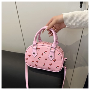 Close-up of pink mini Boston bag with cherry print, dual handles, and long shoulder strap
