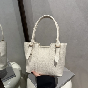Minimalist beige pebble leather bucket bag with top handles and elegant gold hardware