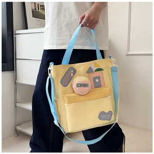 Detail of yellow nylon student tote bag with blue handles and patchwork house pattern