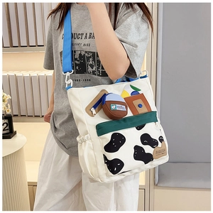 Detail of canvas bag with cow print bottom, blue pocket, and adjustable strap