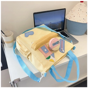 Detail of canvas bag with fashion embroidery, blue straps and mini pouch on a desk