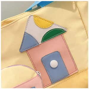 Close-up of vibrant yellow canvas bag with rainbow house patch and front zipper pocket