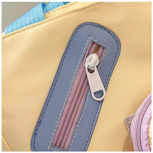 Detail of the yellow canvas tote featuring a blue faux leather zipper pocket and white zipper