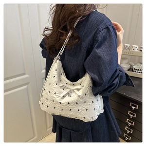 Gros plan du sac cabas blanc rembourré avec broderie et pendentif cœur en argent