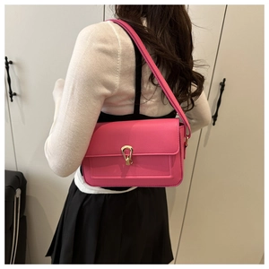 Detail of rose red lychee leather shoulder bag with golden horsebit buckle on a model