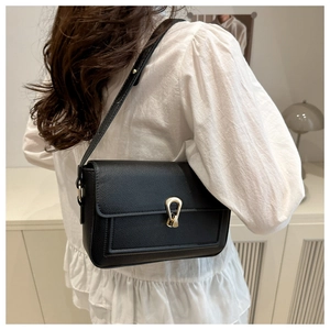 Back view of model wearing a black pebbled leather shoulder bag with gold horseshoe clasp