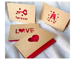 Detail of laser-cut kraft paper love cards with 3D red heart and key elements