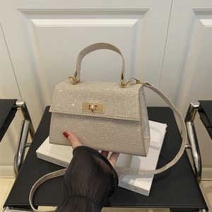 Champagne gold sequin handbag with metallic clasp and strap on a minimalist chair