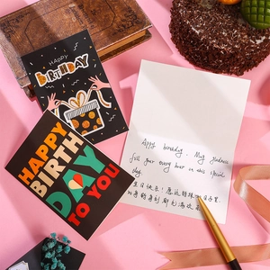 Detailed view of elegant gold-stamped birthday cards with matching black envelopes and inserts