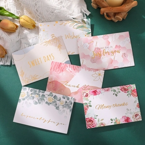 Detailed view of watercolor greeting cards with gold foil lettering and floral designs