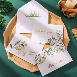 Elegant watercolor thank you cards with green leaves and gold font in a natural setting