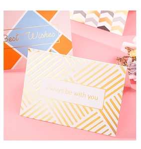 Dettaglio di biglietti d'auguri dorati con testo 'always be with you' su sfondo rosa