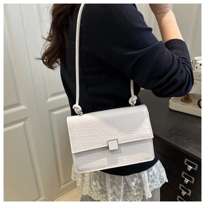 Detailed view of white crocodile texture leather and knotted strap on a square bag