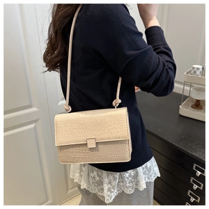 Detail of beige shoulder bag featuring fine crocodile embossing and knot strap design