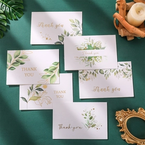 Tarjetas de agradecimiento de acuarela blanca con letras doradas y hojas verdes