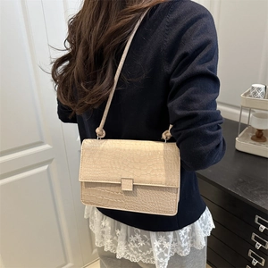 Minimalist beige crossbody bag with crocodile pattern and knotted strap on model